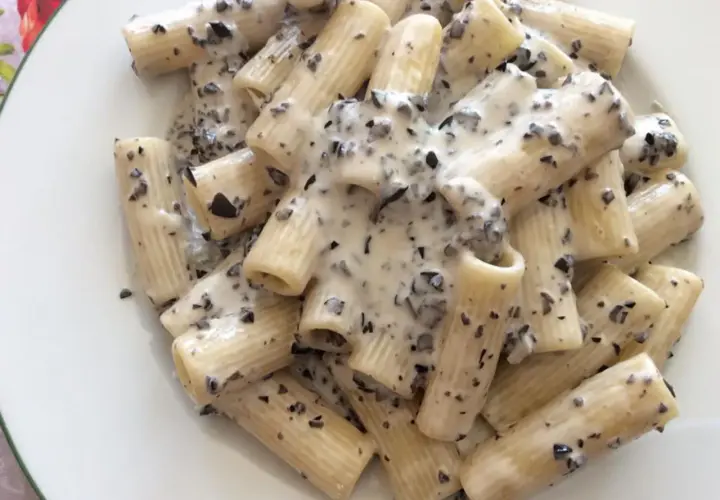 Rigatoni conditi con una cremosa salsa bianca e pezzetti scuri, un invitante piatto di pasta alla cenere.