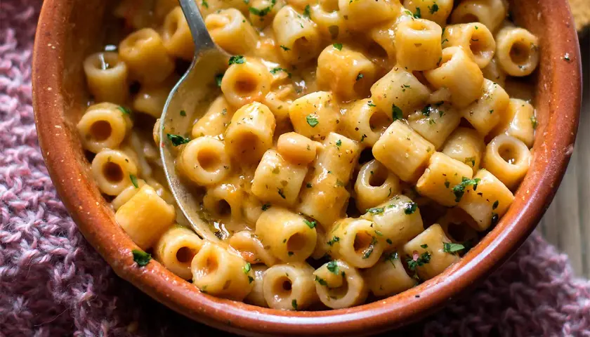 Un piatto fumante di pasta e fagioli, con ditalini e fagioli cannellini in un sugo cremoso, guarnito con prezzemolo tritato.
