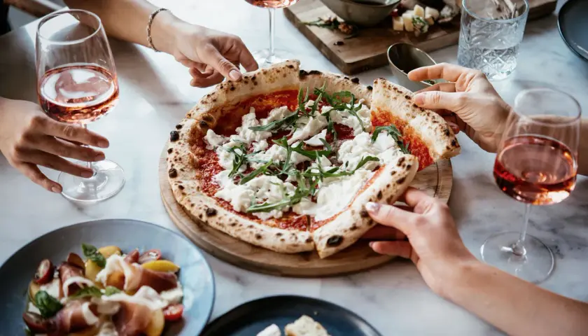 Un delizioso abbinamento pizza con cipolla, accompagnato da un fresco rosato e un'insalata di prosciutto.