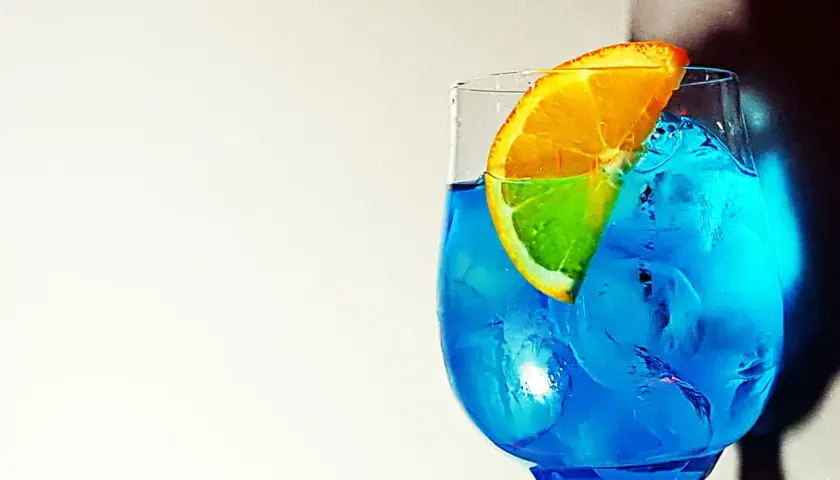 Un rinfrescante spritz blu con una fetta d'arancia, pieno di ghiaccio.
