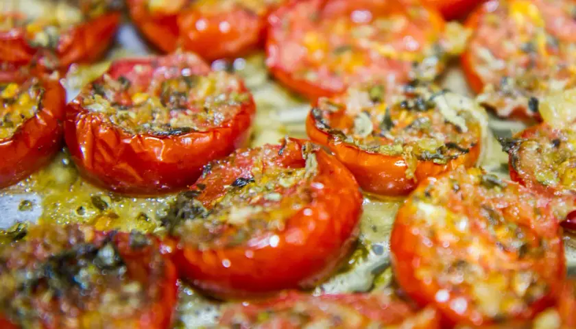 Pomodorini confit cotti al forno, succosi e dorati, pronti per essere gustati.