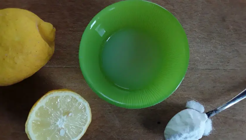 Limoni, succo di limone in ciotola verde e un cucchiaino di bicarbonato al posto del lievito per dolci.