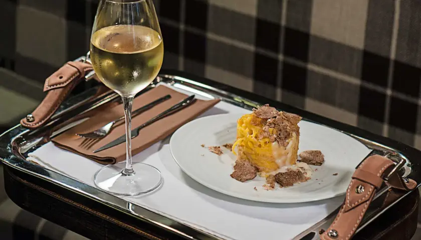 Un bicchiere di vino bianco e un piatto di pasta condita con abbondante tartufo. Un perfetto abbinamento vino tartufo per un'esperienza gourmet.