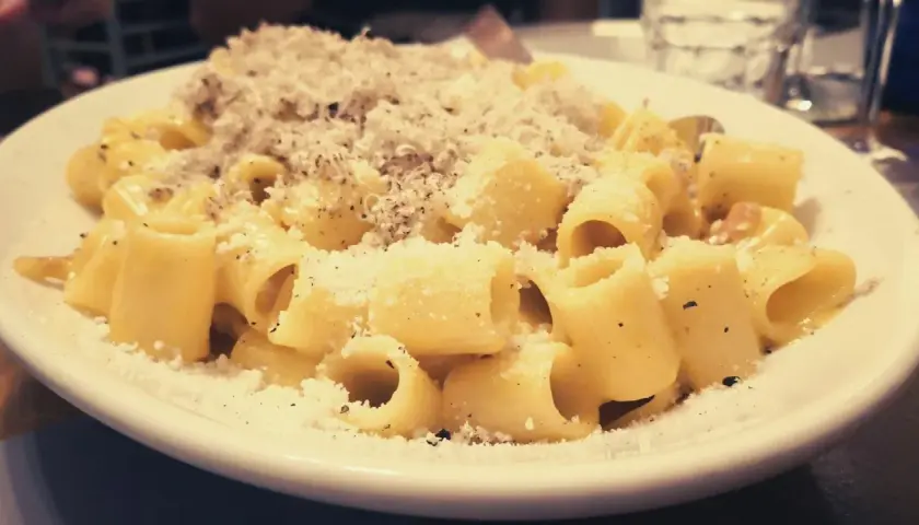 Piatto di carbonara fumante, cosparso di pecorino e pepe. Perfetta con un bicchiere di vino bianco o rosso.