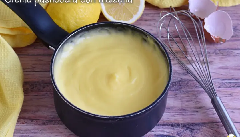 Crema pasticcera liscia e vellutata, preparata con amido di mais, pronta per farcire dolci. Accanto, limoni e gusci d'uovo.