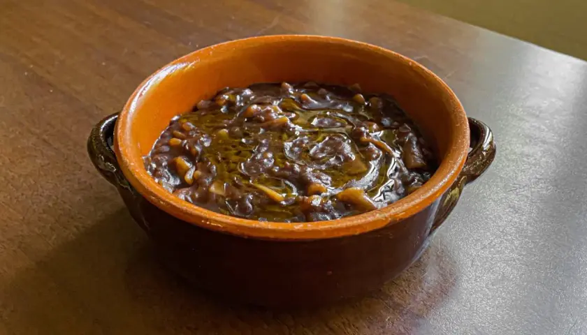 Una ciotola di terracotta con un saporito piatto di pasta e lenticchie, condito con olio d'oliva.