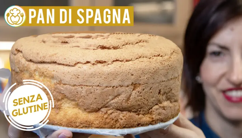 Un soffice pan di spagna senza glutine, dorato e invitante, tenuto da mani sorridenti.
