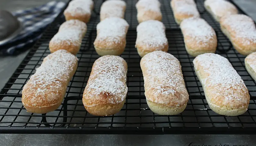 Savoiardi appena sfornati, spolverati di zucchero a velo, pronti per la tua ricetta.