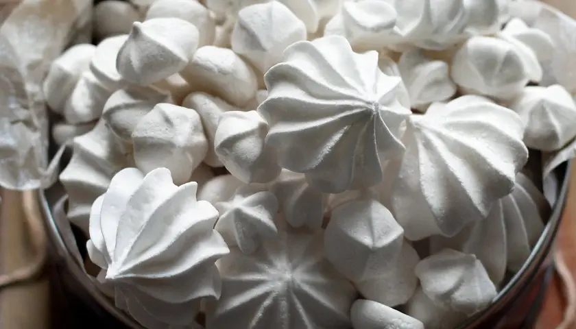 Un cesto pieno di meringhe soffici, perfette per la tua ricetta. Dolci e leggere, invitano a essere gustate.