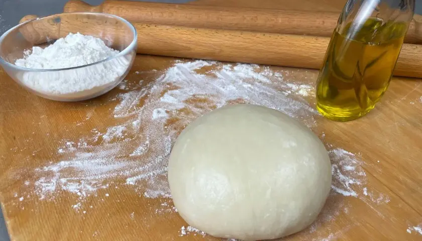 Impasto per pasta brisè con olio e vino bianco, farina e mattarello pronti per creare delizie.