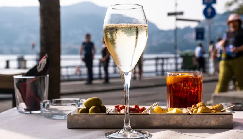 Un bicchiere di bollicine e stuzzichini, il vero significato di aperitivo in riva al lago.