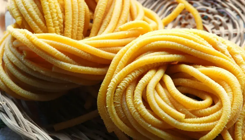 Pici all'aglione, pasta fresca fatta a mano, arrotolata in un cesto di vimini, pronta per essere gustata.