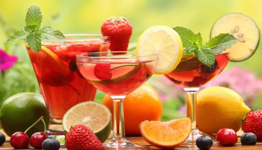 Rinfrescante aperitivo con frutta: cocktail rossi, fragole, ciliegie, mirtilli, limoni e menta.
