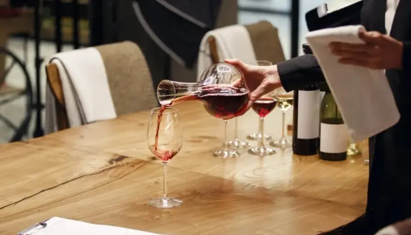 Un sommelier versa il vino rosso in un bicchiere, mostrando cosa fa un sommelier: un'arte di degustazione e servizio.