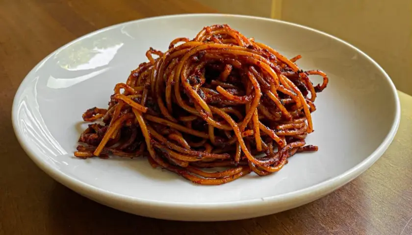 Un piatto di spaghetti all'assassina, conditi con un sugo rosso piccante e saporito, pronti per essere gustati.