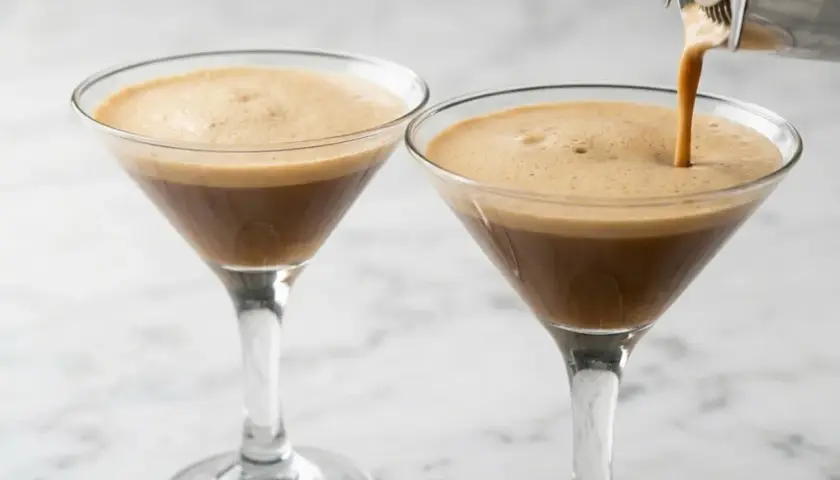 Due bicchieri di caffè shakerato con schiuma cremosa, uno viene riempito da uno shaker.