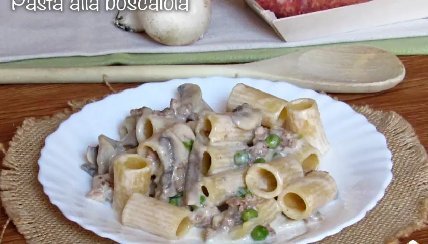 Piatto di pasta alla boscaiola con funghi, piselli e salsiccia, servita su un piatto bianco con un tovagliolo di juta.