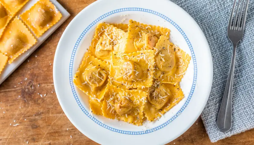 Tortelli di zucca ricetta originale, un piatto invitante con pasta fresca ripiena, condita con parmigiano e pepe nero.