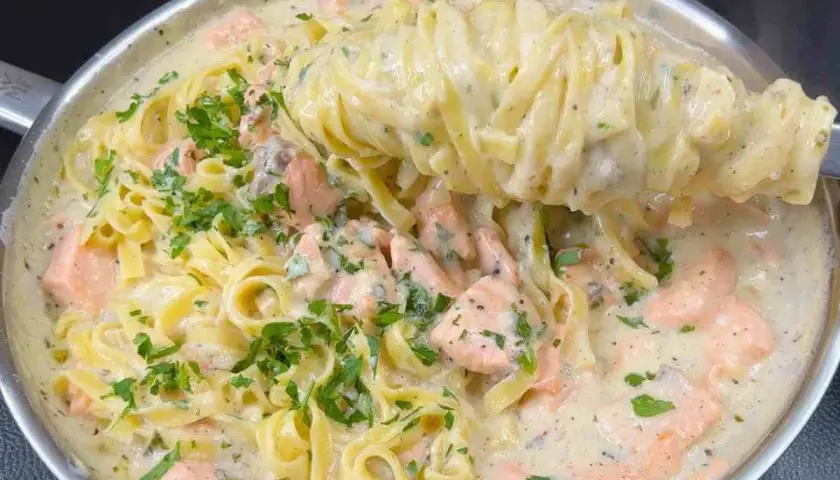 Un primo piatto cremoso di pasta panna e salmone, guarnito con prezzemolo fresco.