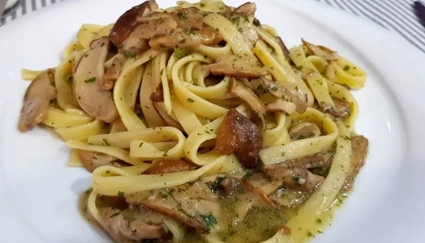 Un piatto invitante di tagliatelle ai funghi porcini, condite con erbe aromatiche e un sugo saporito.