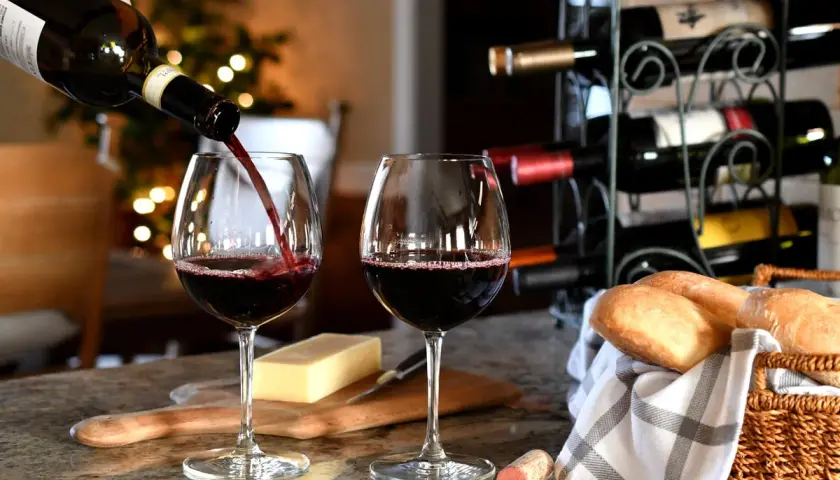 Versare vino rosso in un bicchiere, con pane e formaggio. Un promemoria su come conservare il vino rosso per gustarlo al meglio.
