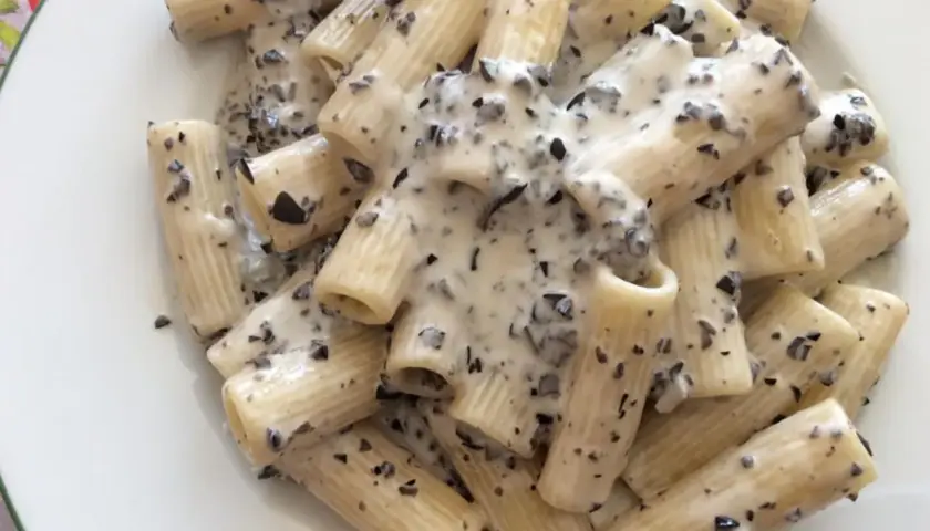 Rigatoni conditi con una cremosa salsa bianca e pezzetti scuri, un invitante piatto di pasta alla cenere.