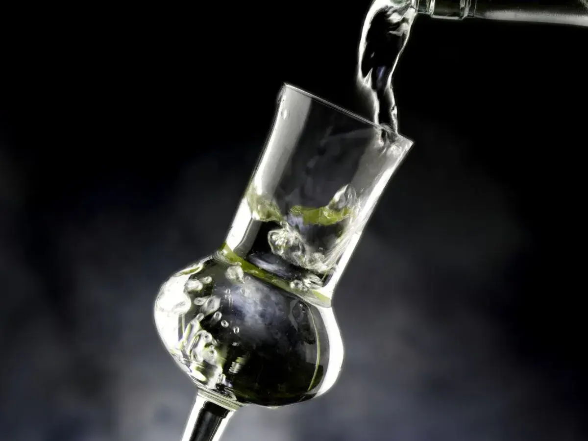 Versando grappa in un bicchiere speciale, creando bollicine e un'atmosfera invitante.
