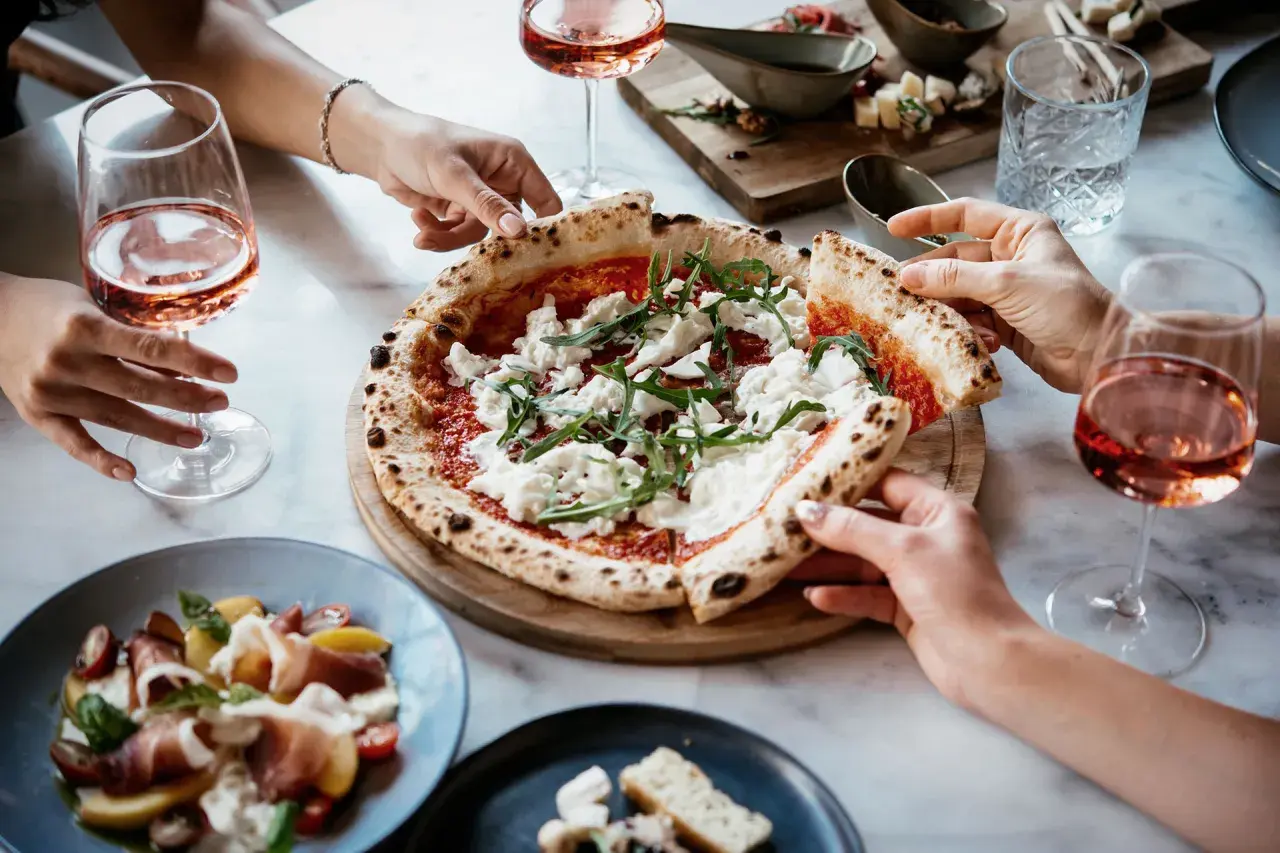 Un delizioso abbinamento pizza con cipolla, accompagnato da un fresco rosato e un'insalata di prosciutto.