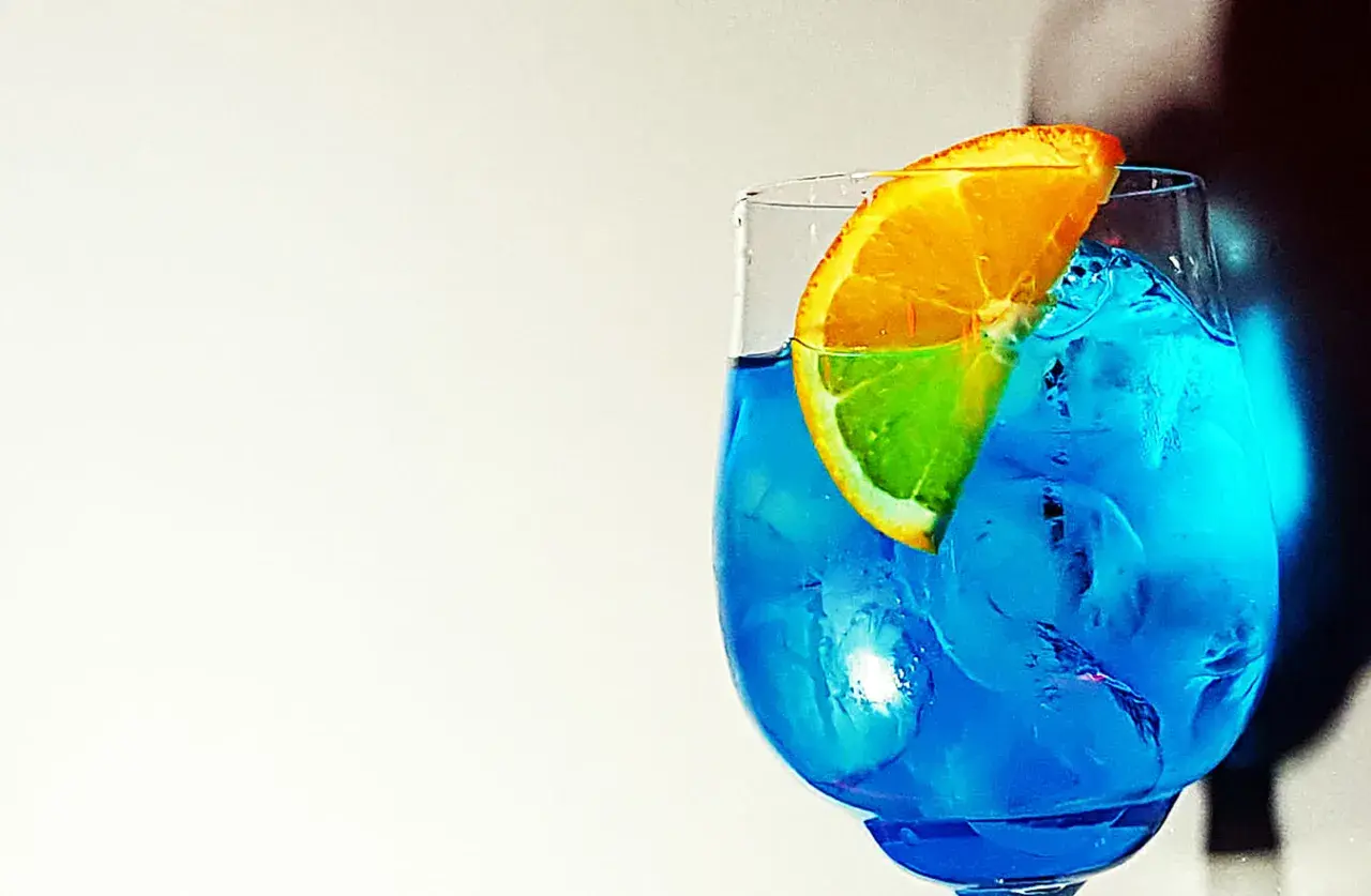 Un rinfrescante spritz blu con una fetta d'arancia, pieno di ghiaccio.