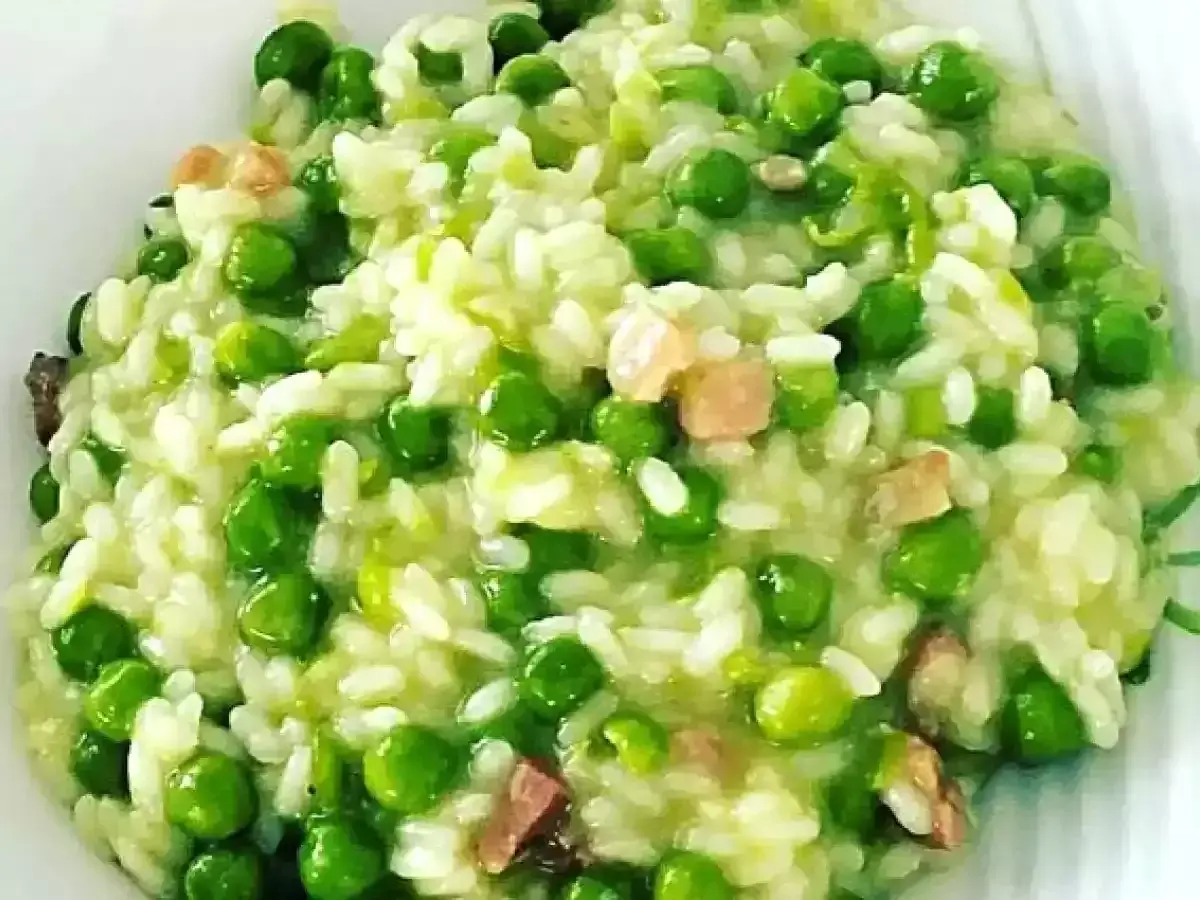 Un cremoso piatto di risi e bisi, con piselli verdi brillanti e cubetti di pancetta croccante, pronto per essere gustato.
