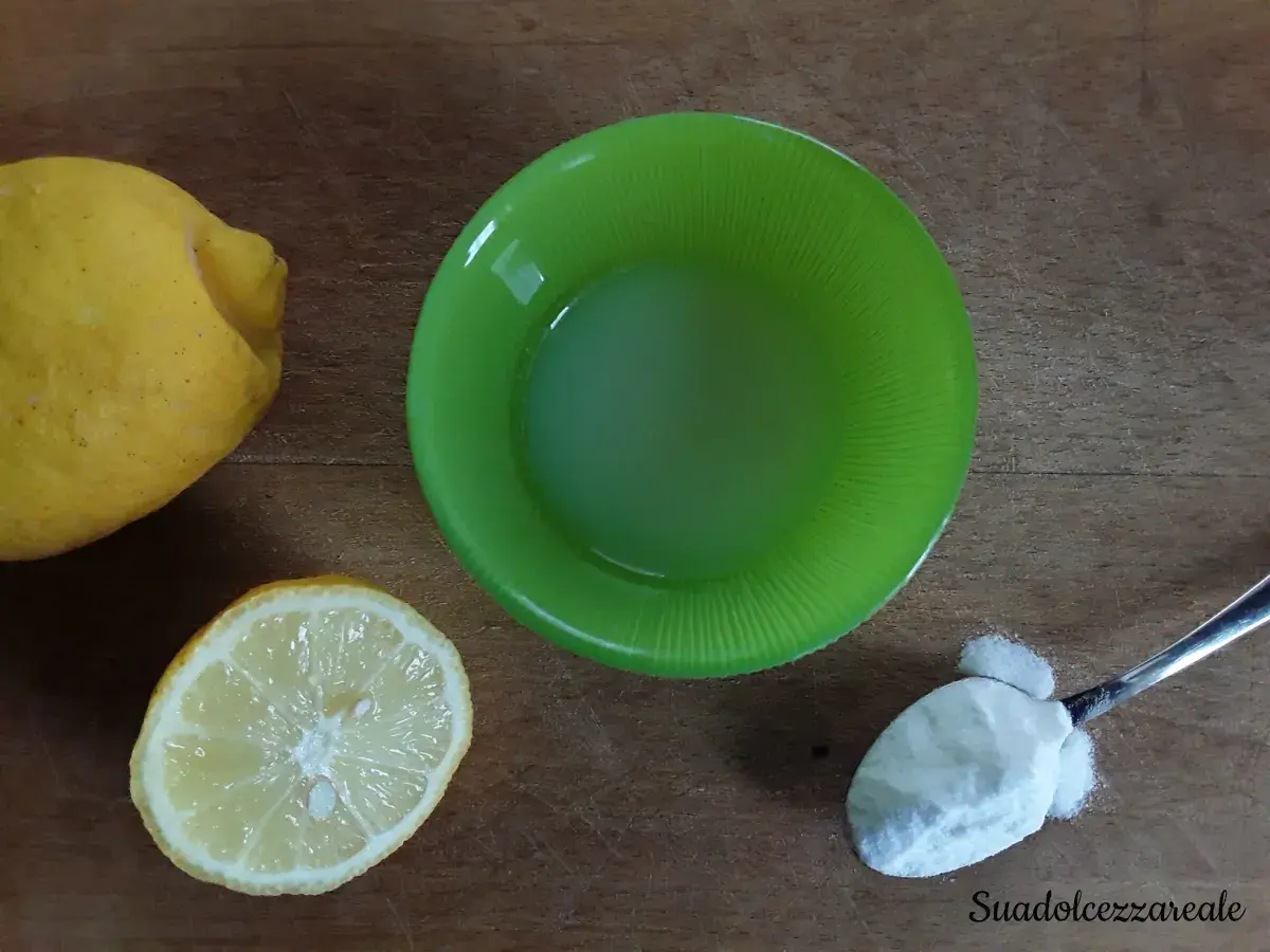 Limoni, succo di limone in ciotola verde e un cucchiaino di bicarbonato al posto del lievito per dolci.