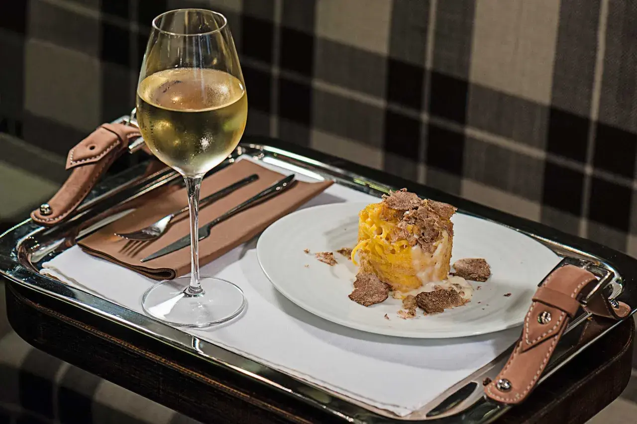 Un bicchiere di vino bianco e un piatto di pasta condita con abbondante tartufo. Un perfetto abbinamento vino tartufo per un'esperienza gourmet.