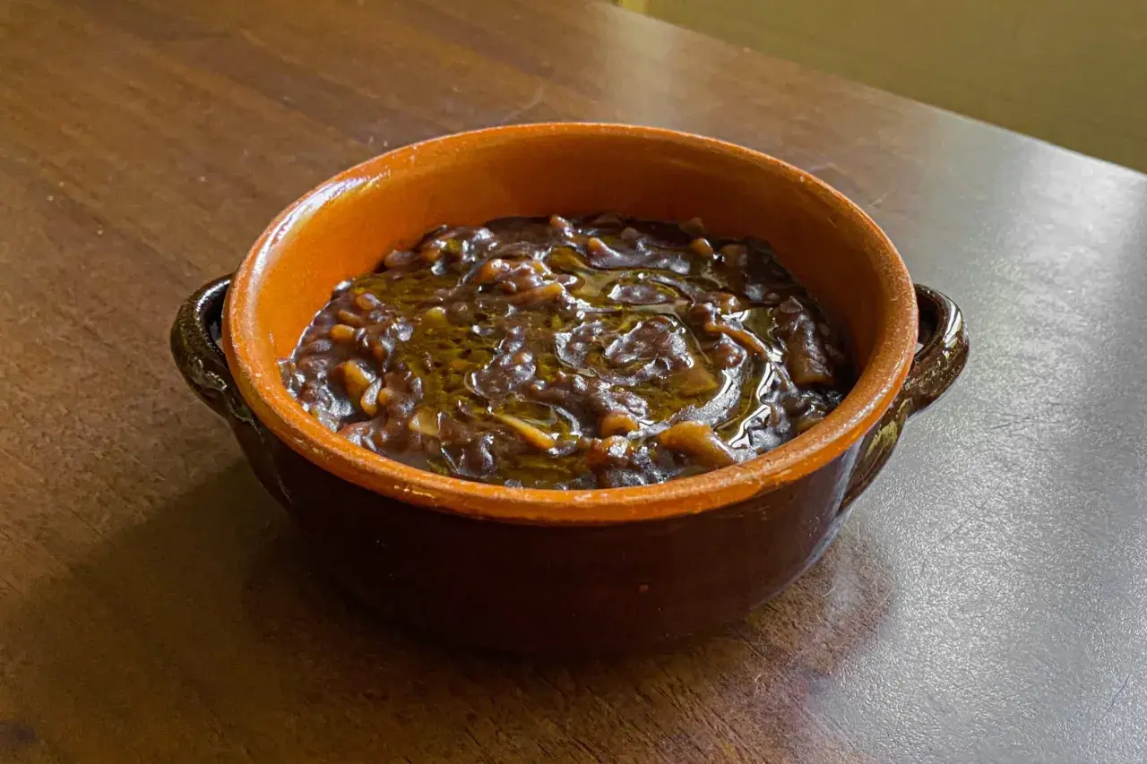 Una ciotola di terracotta con un saporito piatto di pasta e lenticchie, condito con olio d'oliva.