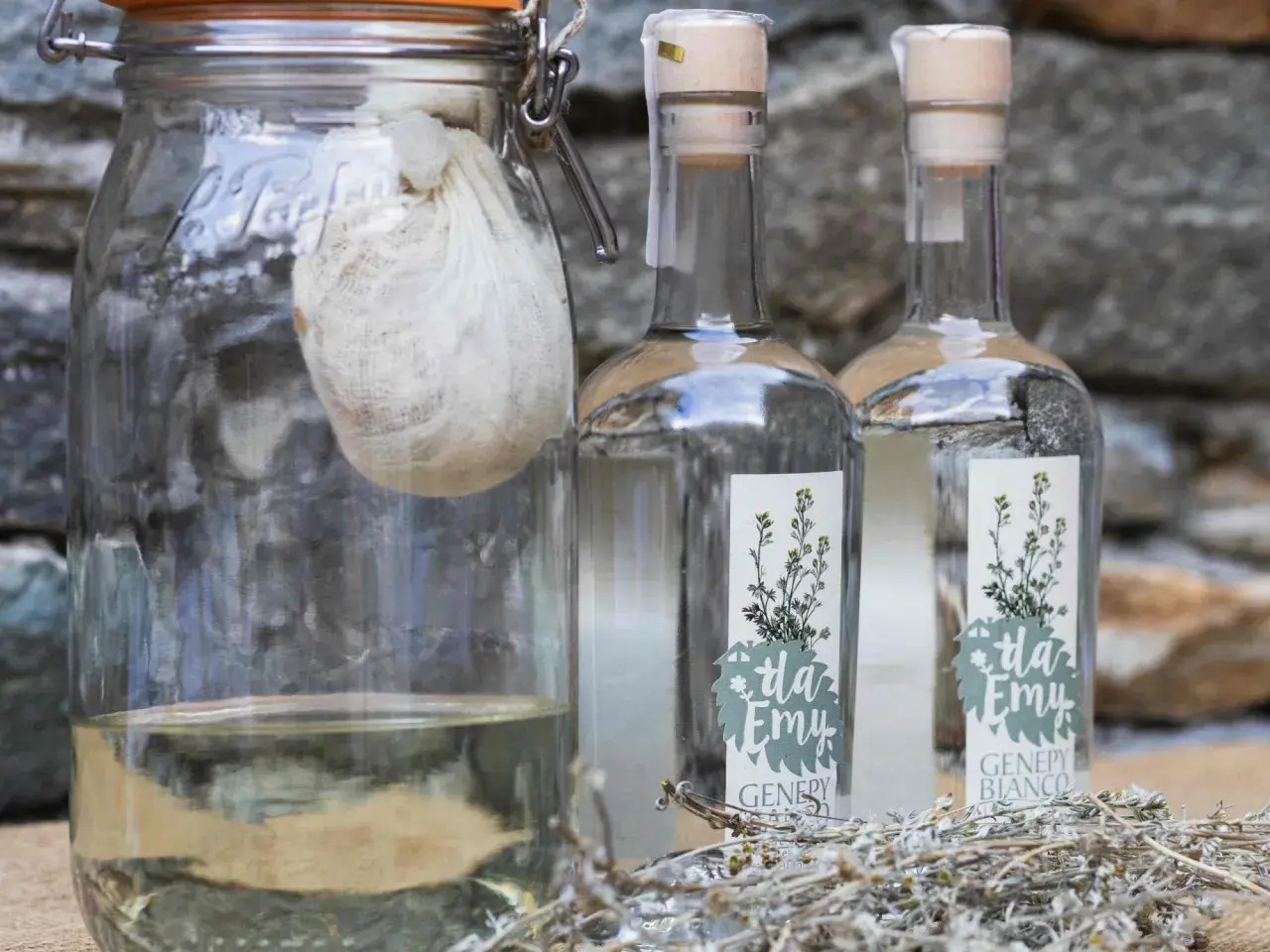 Vaso con infuso di erbe e due bottiglie di genepy, pronti per la ricetta.