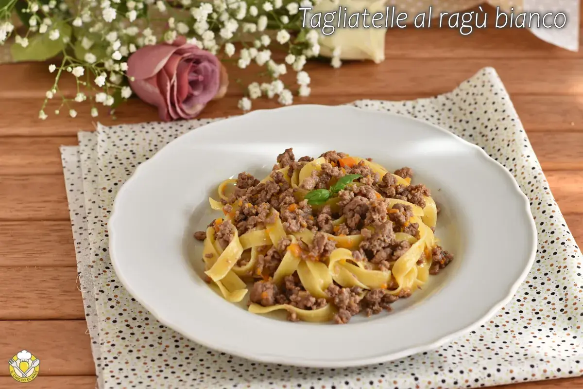 Tagliatelle al ragù bianco, un piatto gustoso con carne macinata e verdure, guarnito con basilico.