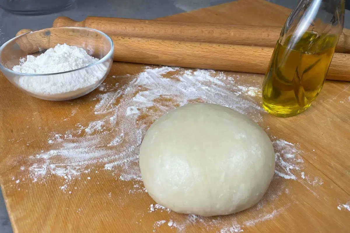 Impasto per pasta brisè con olio e vino bianco, farina e mattarello pronti per creare delizie.