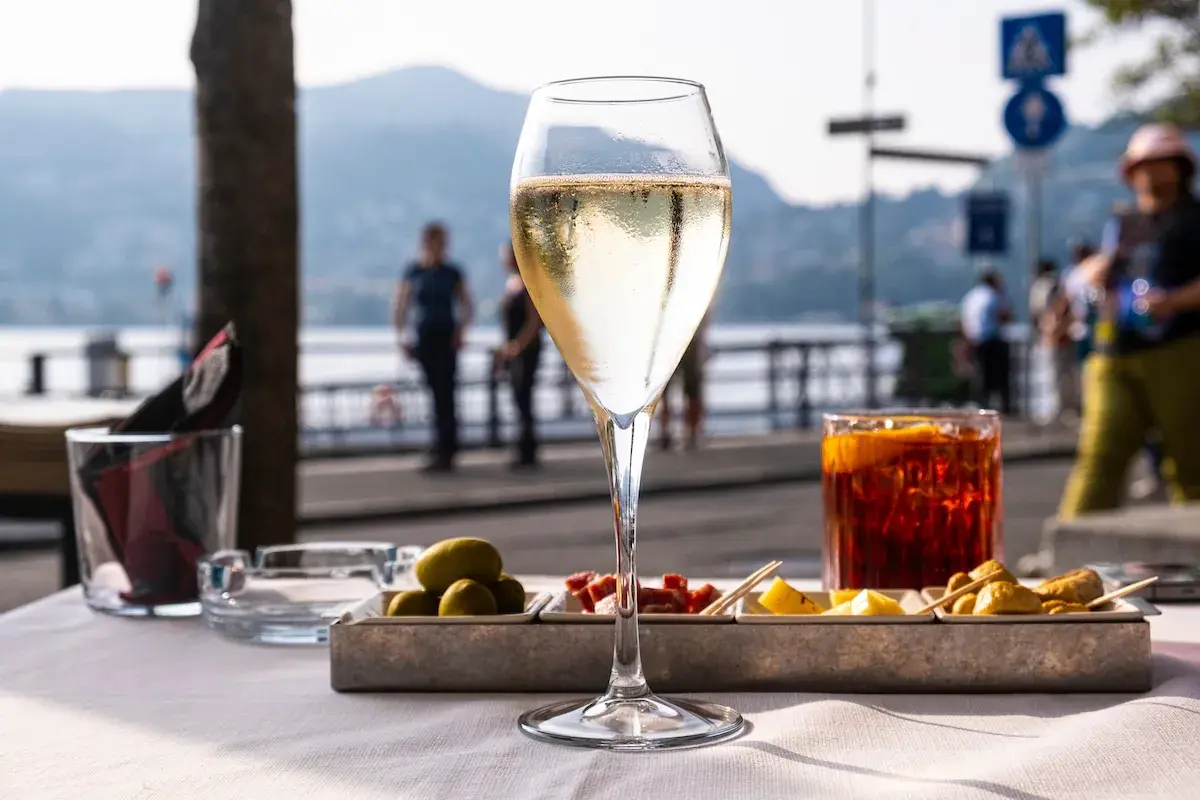Un bicchiere di bollicine e stuzzichini, il vero significato di aperitivo in riva al lago.