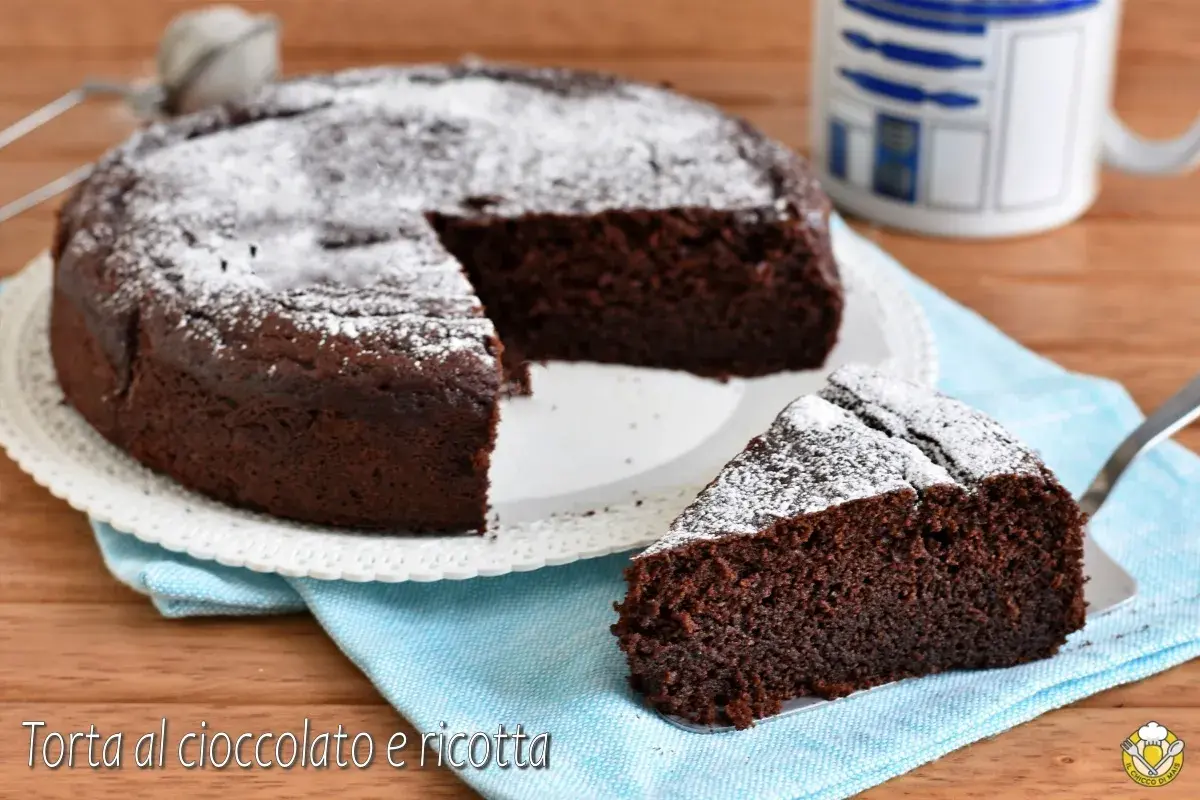 Una deliziosa torta al cioccolato e ricotta, cosparsa di zucchero a velo, con una fetta servita su un tovagliolo azzurro.