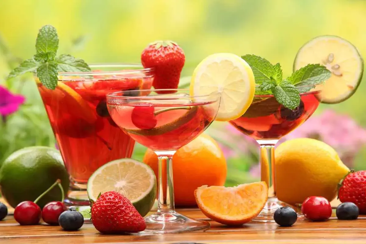 Rinfrescante aperitivo con frutta: cocktail rossi, fragole, ciliegie, mirtilli, limoni e menta.