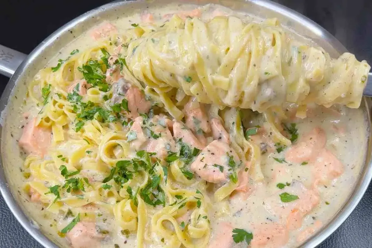 Un primo piatto cremoso di pasta panna e salmone, guarnito con prezzemolo fresco.