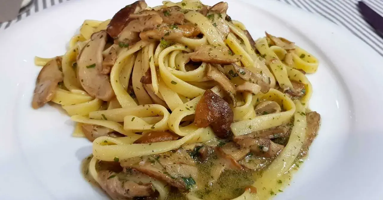 Un piatto invitante di tagliatelle ai funghi porcini, condite con erbe aromatiche e un sugo saporito.