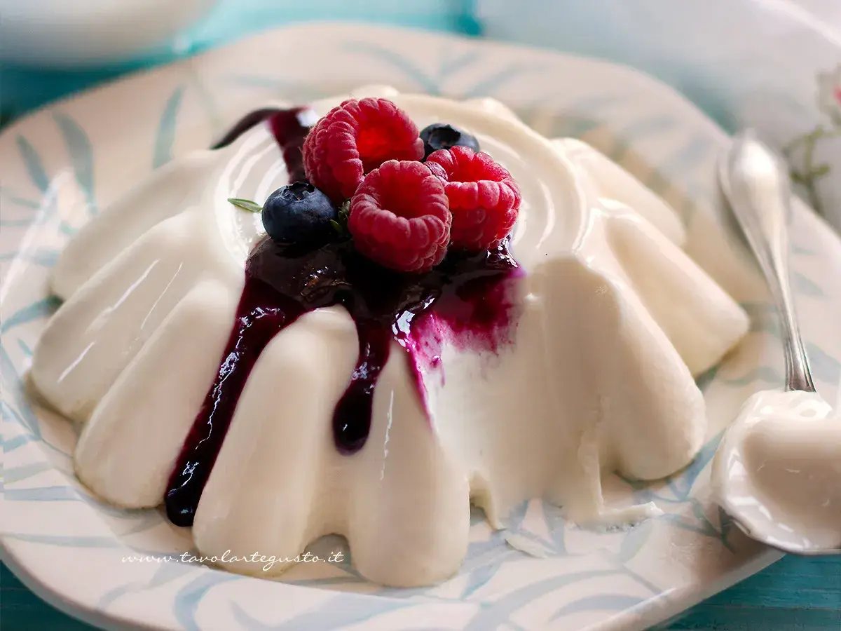 Deliziosa panna cotta con frutti di bosco e salsa ai mirtilli, servita su un piatto decorato.