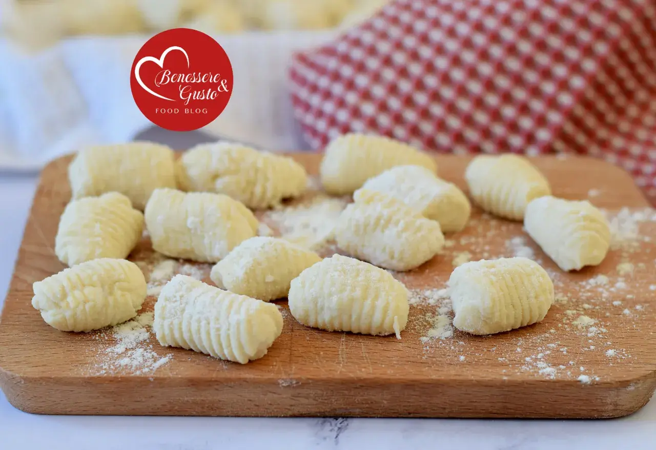 Gnocchi di ricotta freschi, pronti per essere cucinati, spolverati di farina su un tagliere di legno.