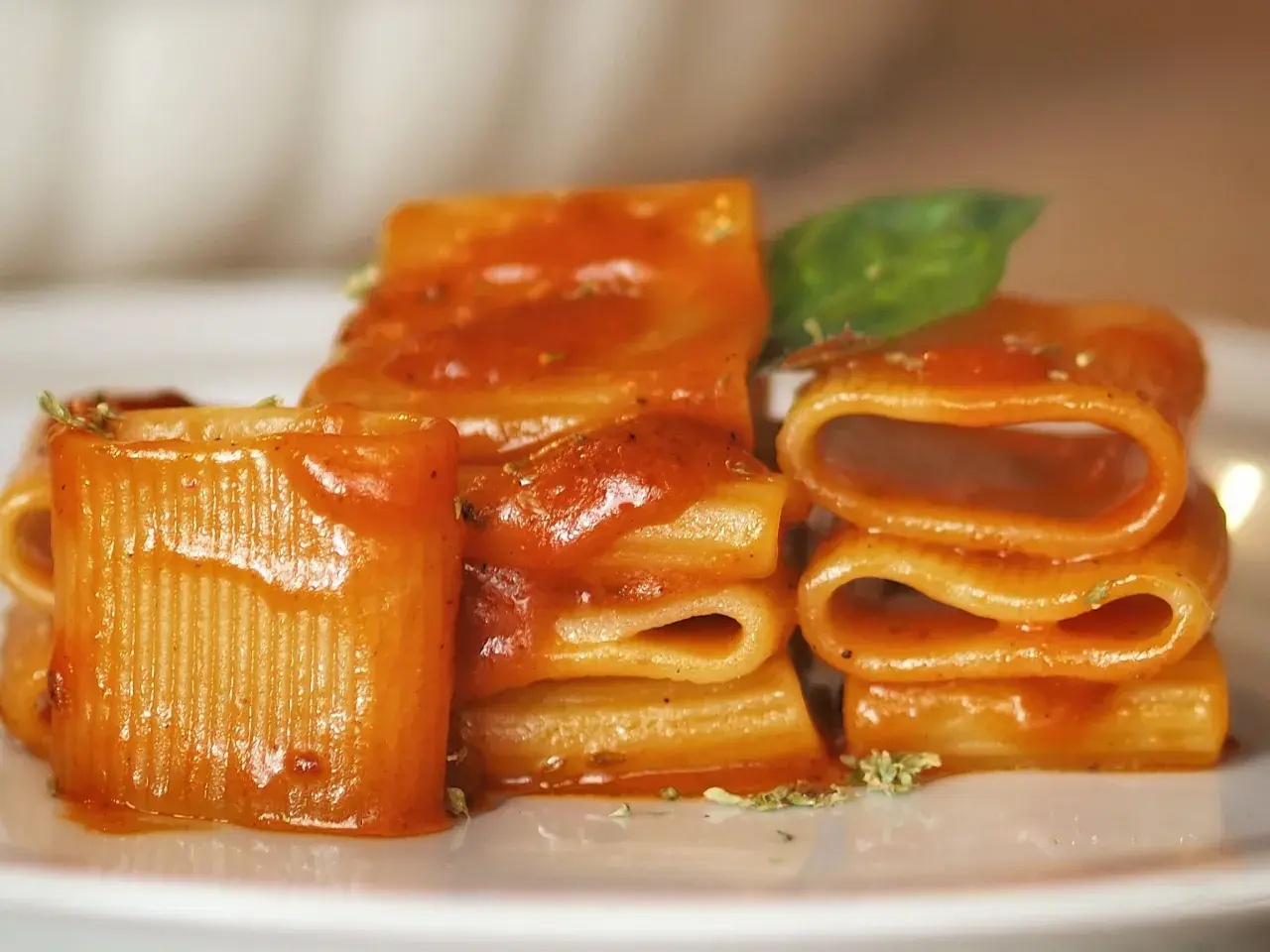 Un primo piatto invitante: paccheri conditi con un sugo rosso vivace, un classico della **pasta allo scarpariello**, guarnito con basilico fresco.