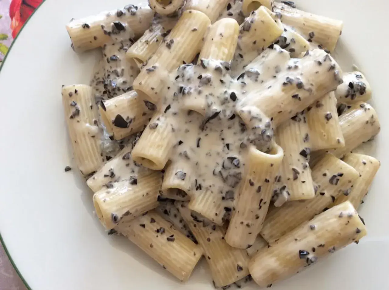 Rigatoni conditi con una cremosa salsa bianca e pezzetti scuri, un invitante piatto di pasta alla cenere.