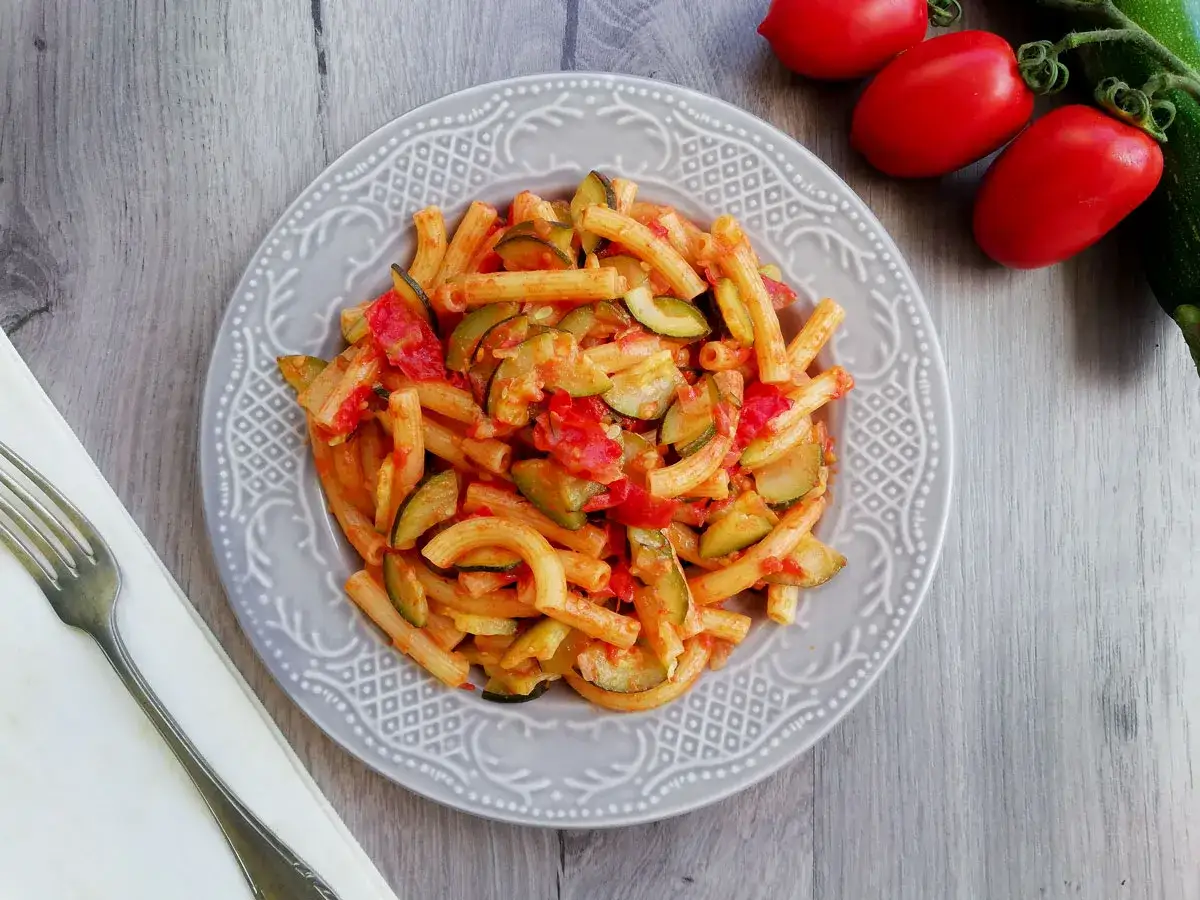 Piatto di pasta con zucchine e pomodorini, un classico estivo. Fresca e colorata, pronta per essere gustata.