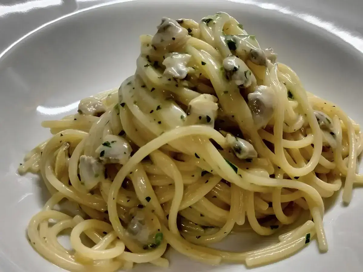 Un piatto invitante di spaghetti alle vongole, con pasta dorata e molluschi succulenti, guarnito con prezzemolo fresco.