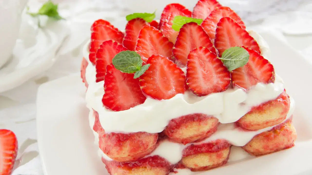 Delizioso tiramisù fragola con strati di savoiardi, crema e fragole fresche, guarnito con menta.