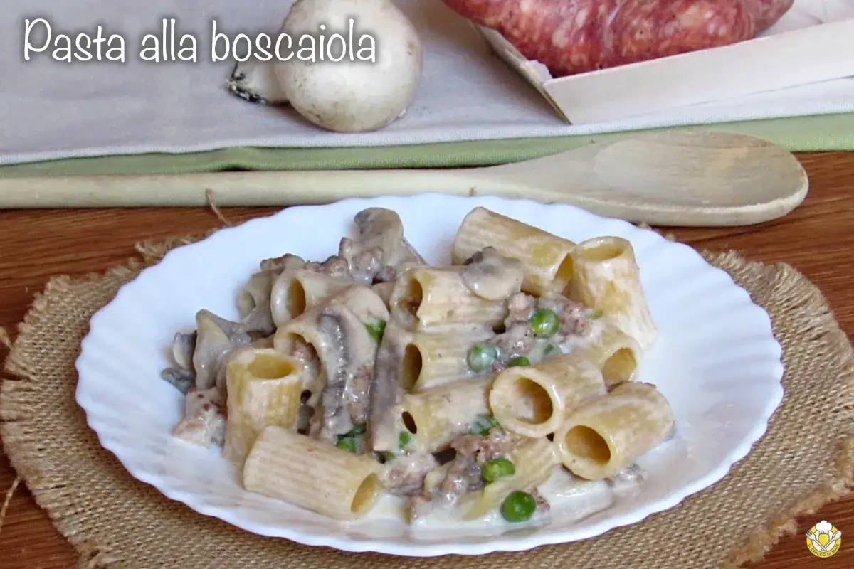 Piatto di pasta alla boscaiola con funghi, piselli e salsiccia, servita su un piatto bianco con sfondo rustico.