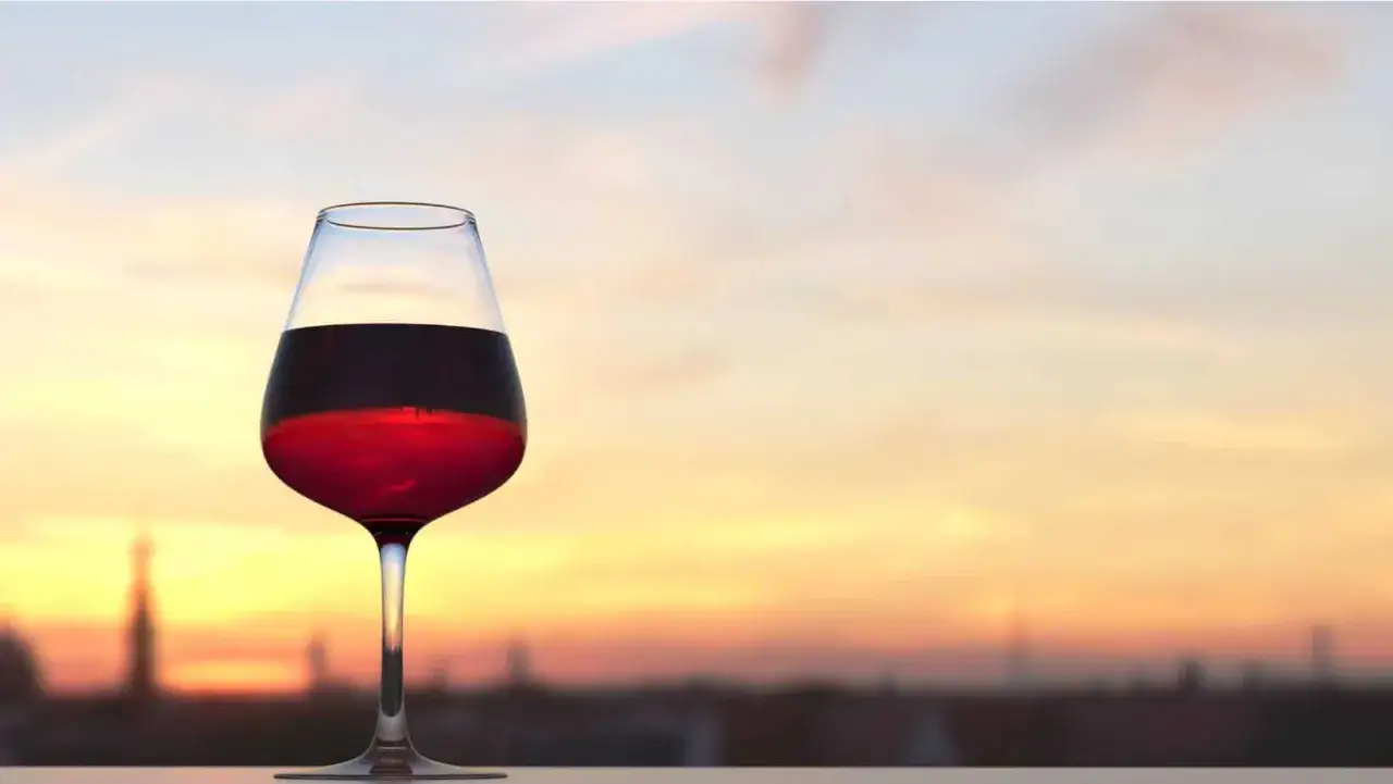Calice di rosso di Montalcino al tramonto, perfetto per i tuoi abbinamenti con carni rosse e formaggi stagionati.